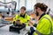 Side view of Caucasian engineer or technician workers man and woman check piece of machine or a part from robotic arm in factory