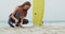 Side view of Caucasian female surfer tying surfboard leash on her leg surfboard at beach 4k