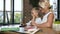 Side view of caucasian middle aged woman with little grandchild sitting at the table in the cozy office room telling