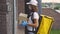 Side View of the Caucasian Woman Courier Going to the Clients Home, Holding the Paper Boxes, Wearing the Protective Mask