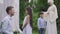 Side view of charming little Middle Eastern girl talking with Caucasian man with wedding bouquet as blurred boy and