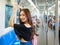 Side view of cheerful Asian female passenger standing train and holding handrail while looking at camera. Idea for city life of