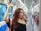 Side view of cheerful Asian female passenger standing train and holding handrail while looking at outside. Idea for city life of