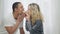 Side view of cheerful millennial interracial couple eating croissant from both sides in bedroom in the morning. Positive