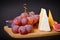 Side view of Cheeseboard platter with hard and soft mould cheese, grape and segmented fig on wooden board