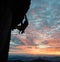 Side view of climber silhouette in action at sunset over mountain peaks. Clouds, colorful sky on background. Copy space