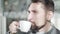 Side view close-up of businessman drinking coffee in the morning. Portrait of satisfied Caucasian handsome man with