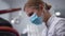 Side view close-up concentrated female dentist talking to patient in dental chair using tools. Focused beautiful