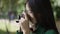 Side view close-up of curios Asian woman taking photo of nature on camera smiling looking away. Portrait of talented