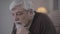 Side view close-up of desperate Caucasian old man sighing. Portrait of brown-eyed grey-haired retiree spending time at