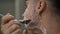 Side view close-up man shaving cheek with razor in slow motion. Headshot portrait of young Caucasian confident man