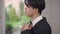 Side view close-up of young Asian man trying on bow tie indoors looking away in mirror. Portrait of serious stylish