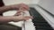 Side view closeup of a child`s pair of hands playing the piano with an adult`s hands behind doing the same