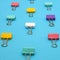 Side view of colored binder clips on a blue paper background, selective focus