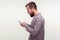 Side view of concentrated bearded man using smartphone looking serious focused, reading message. white background