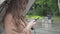 Side view of concentrated Caucasian brunette girl using smartphone outdoors on rainy day. Close-up portrait of focused