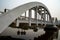 Side view of concrete white railroad bridge with reflection in the river and blue sky background.