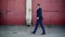 Side view of confident African American man in formal business suit walking in urban slum taking off sunglasses. Wide