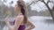 Side view of confident Caucasian sportswoman running along lake shore in park. Slender brunette girl jogging outdoors in