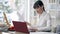 Side view of confident focused young businesswoman looking at documents and typing on laptop keyboard. Concentrated slim