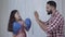 Side view of confident little Middle Eastern girl boxing father`s hands indoors. Pretty daughter training with parent at