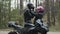 Side view of confident motorbiker putting on helmet and loving girlfriend fastening it. Young interracial couple