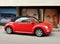 Side view of convertible red Volkswagen Beetle A5 at the roadside, with billboards on its back