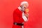 Side view of crazy hungry elderly man with gray beard wearing santa claus costume holding in hands sugary candy, biting