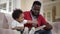 Side view curios African American son enjoying leisure with man reading book. Cute hyperactive toddler boy listening