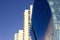 Side view of a curved blue glass window wall of a modern and elegant corporative high-rise building, next to a yellowish classical