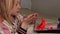 Side view of a cute fair-haired little girl making plasticine man in her room