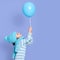 Side view of cute little girl holding balloon in hands, looking up on her toy, wearing striped turtleneck, cap and scarf in