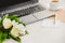 Side view of a deck with computer, bouquet of peonies flowers, cup of coffee, empty card and kraft envelope. White rustic wooden b