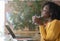 Side view of delighted black girl enjoying coffee at cafe