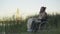 Side view of depressed disabled man sitting in wheelchair at sunset and looking away. Portrait of paralyzed hopeless