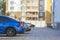 Side view detail of cars row parked in paved yard parking lot area on blurred building background on bright sunny day.