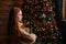 Side view of dissatisfied young woman holding Christmas gift box on background of xmas tree.