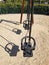 Side view of double swing bench with metal ropes on sand ground of playground. Closeup of empty swing on children playground.