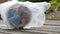 Side view of the Earth in polyethylene disposable package on wooden background. Concept of ecological problems. Stop