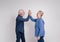 Side view of ecstatic senior couple giving high-five to each other and screaming on white background