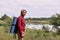 Side view of eldery man with backpack and blue rug, enjoying of admiring majestic view of river while walking in wonderful