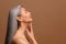 Side view at enchanting topless middle aged Asian woman isolated on brown background