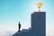 Side view of european businessman standing on stairs to golden winner\\\'s cup with obstacle on blue sky background. Success