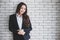 Side view of excited ethnic female entrepreneur in classy jacket leaning on wall in modern office and smiling  with happy, fun