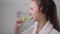 Side view face of concentrated slim beautiful young woman in headphones brushing teeth in slow motion. Close-up of