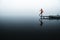 Side view of fashioned young woman sitting on wooden dock looking at view on a misty morning
