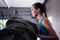 Side view of female athlete pushing tire in gym