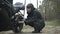 Side view of female biker sitting at motorcycle and checking motorbike. Confident stylish Caucasian brunette woman