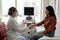 Side view of female clinician and patient shaking hands in medical office