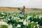 Side view of a female farmer squatting proudly holding a head of cabbage in front of her.